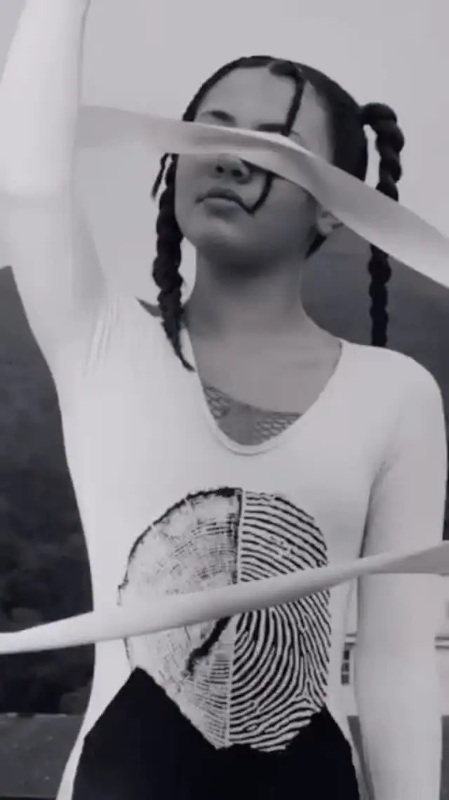 Modelo em preto e branco com camiseta estampada com a marca do FFW, anéis de árvore unidos a uma impressão digital