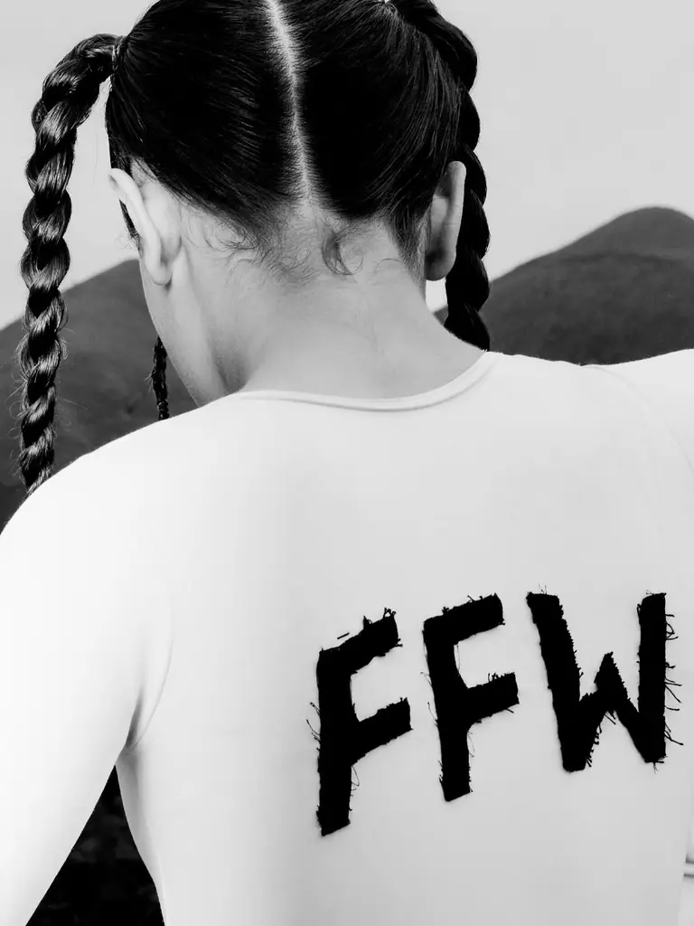 Modelo de costas com a sigla FFW pintada em preto, diante das montanhas de Nova Friburgo